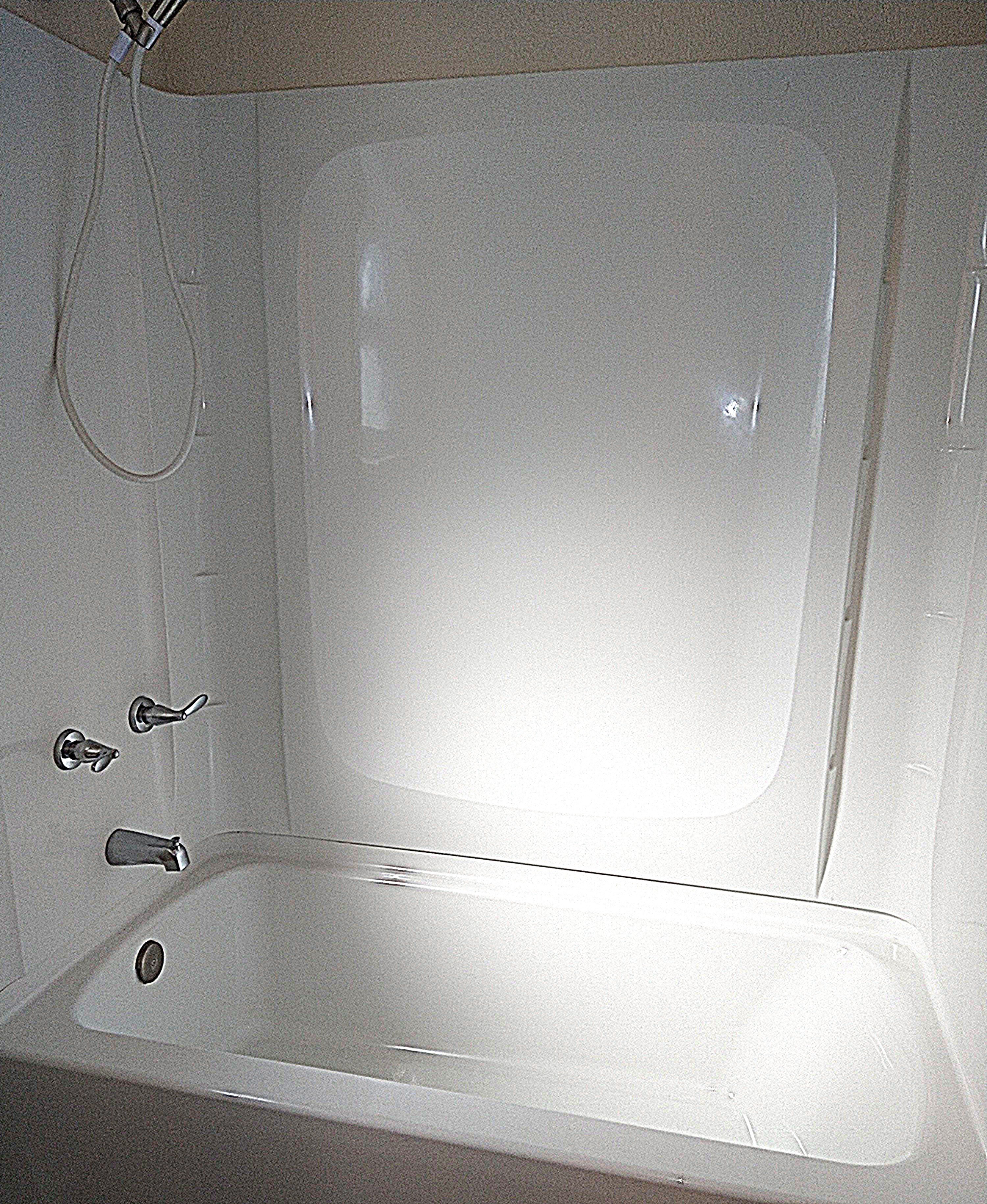 A white bathtub with a shower head and faucet.